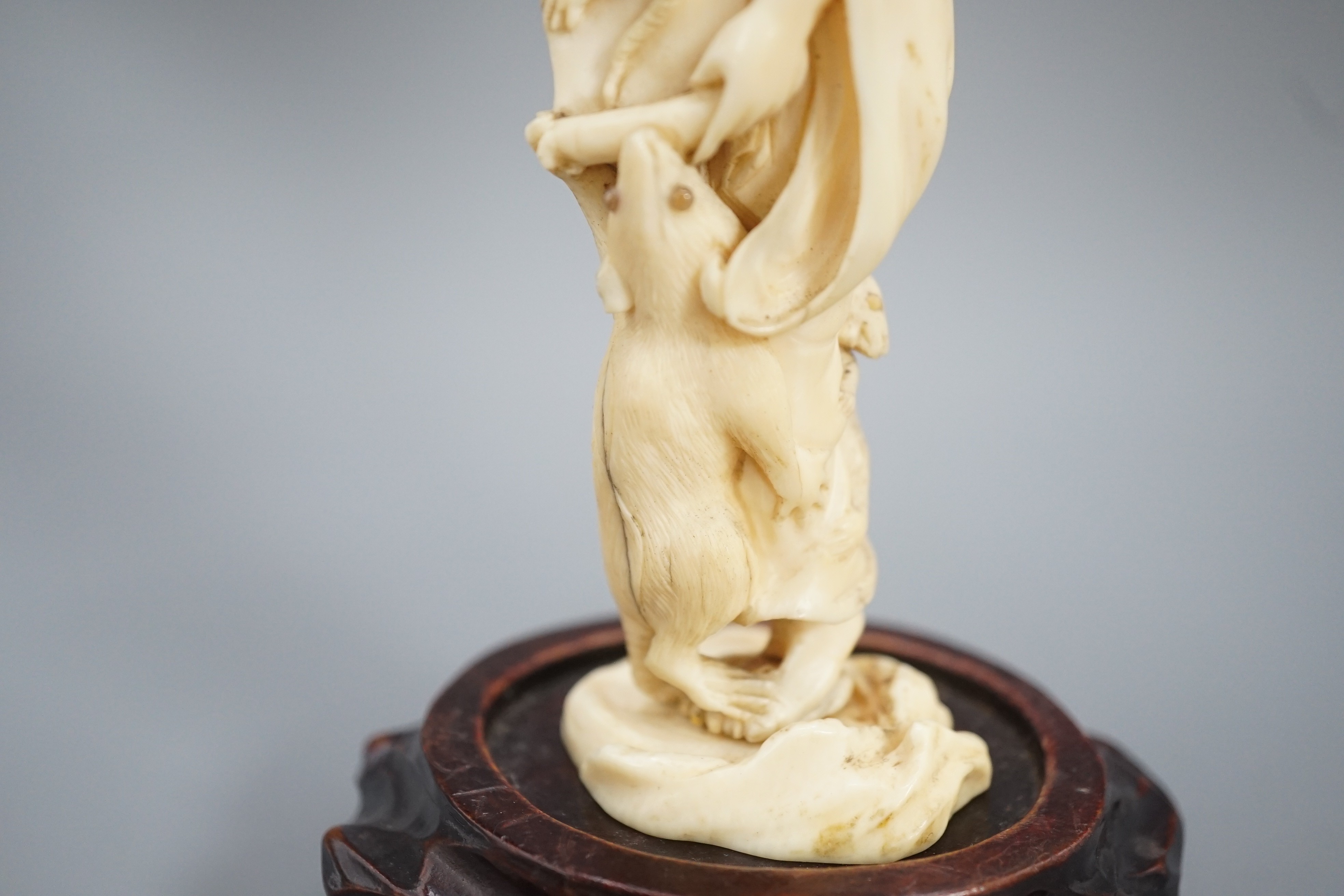 A Japanese ivory okimono of a man with giant rats clambering over him, signed, late 19th century 12.5cm, wood stand